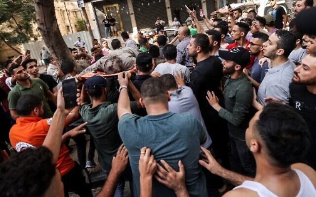 Des secouristes palestiniens évacuent le corps d'un homme, tué lors d'une frappe aérienne israélienne sur la ville de Gaza, le 5 août 2022. (Crédit : MAHMUD HAMS / AFP)