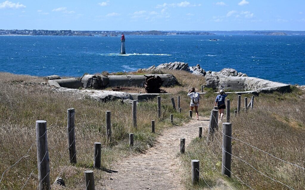 Des touristes avancent vers les épaves d'un canon d'artillerie et d'un bunker allemand sur l'île Cézembre, au large de Saint-Malo, le 5 août 2022. (Crédit : Damien MEYER / AFP)
