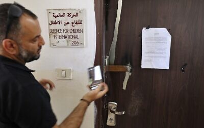 Un homme photographiant un ordre militaire israélien sur la porte fermée de Defense for Children-International in Palestine, après avoir été perquisitionnée par Tsahal dans la ville de Ramallah, en Cisjordanie, le 18 août 2022. (Crédit : Abbas Momani/AFP)
