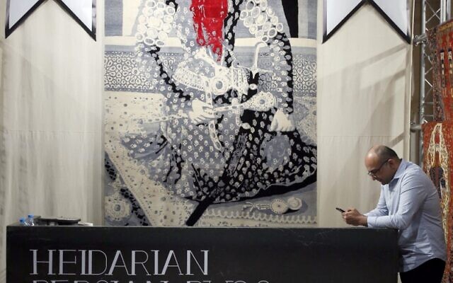 Un employé à côté d'un tapis moderne Azebaijani représentant le roi Fath-Ali Shah à la 29e exposition du tapis artisanal organisé dans la capitale iranienne de Téhéran, le 26 août 2022. (Crédit : AFP) Un employé à côté d'un tapis moderne Azebaijani représentant le roi Fath-Ali Shah à la 29e exposition du tapis artisanal organisé dans la capitale iranienne de Téhéran, le 26 août 2022. (Crédit : AFP)
