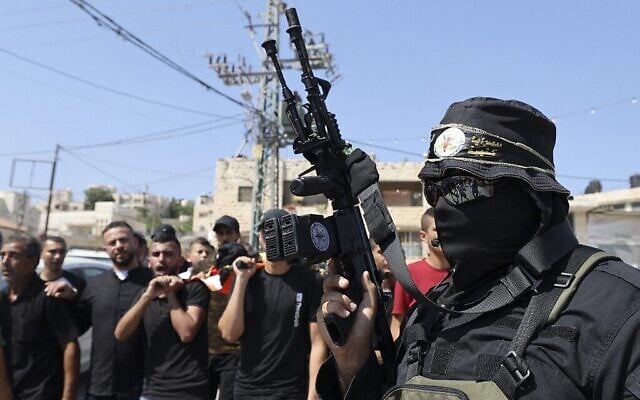 Un tireur affilié au groupe terroriste palestinien du Jihad islamique défilant alors que des hommes portent le corps de Dirar al-Kafrayni, tué lors d'affrontements avec les troupes israéliennes dans la ville de Jénine en Cisjordanie, lors de ses funérailles dans le camp de réfugiés de Jénine, le 2 août 2022. (Crédit : Jaafar Ashitiyeh/AFP)