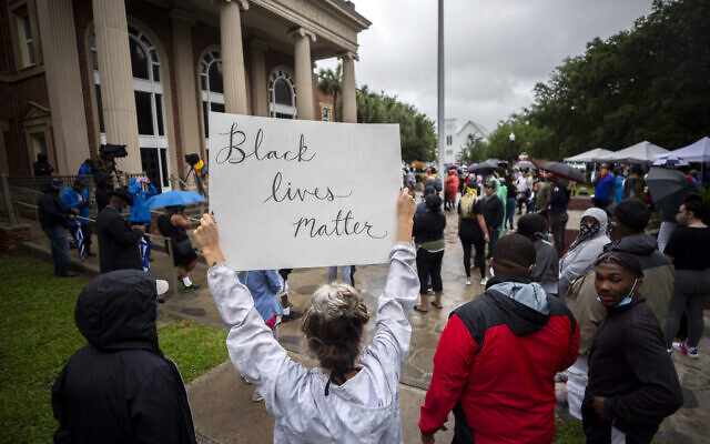 Des manifestants se rassemblent devant le palais de justice lors d'une audience préliminaire pour Travis McMichael, Gregory McMichael et William Bryan, les trois hommes sont accusés d'avoir tiré sur Ahmaud Arbery alors qu'il courait dans leur quartier, à Brunswick, en Géorgie, le 4 juin 2020. (Crédit : Stephen B. Morton/AP)