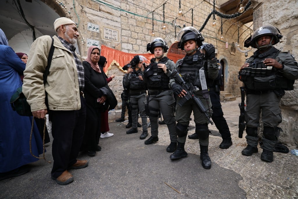 Des Palestiniens font face à des agents de la Police des frontières israélienne qui patrouillent devant la Porte des lions dans la Vieille Ville de Jérusalem, le 17 avril 2022. (Crédit: Ahmad Gharabli/AFP)