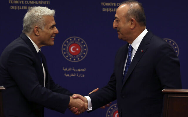 Le ministre turc des Affaires étrangères r Mevlut Cavusoglu, à droite, et le ministre des Affaires étrangères israélien de l'époque, Yair Lapid, se serrent la main à Ankara, en Turquie, le 23 juin 2022. (Crédit : AP Photo/Burhan Ozbilici) Le ministre turc des Affaires étrangères r Mevlut Cavusoglu, à droite, et le ministre des Affaires étrangères israélien de l'époque, Yair Lapid, se serrent la main à Ankara, en Turquie, le 23 juin 2022. (Crédit : AP Photo/Burhan Ozbilici)