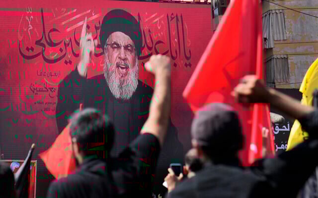 Le chef du Hezbollah, Sheik Hassan Nasrallah, s'exprimant via une liaison vidéo, tandis que ses partisans lèvent la main, lors de la fête sainte chiite de l'Achoura, dans la banlieue sud de Beyrouth, au Liban, le 9 août 2022. (Crédit : AP Photo/Hussein Malla) Le chef du Hezbollah, Sheik Hassan Nasrallah, s'exprimant via une liaison vidéo, tandis que ses partisans lèvent la main, lors de la fête sainte chiite de l'Achoura, dans la banlieue sud de Beyrouth, au Liban, le 9 août 2022. (Crédit : AP Photo/Hussein Malla)
