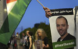 Des manifestants brandissant le drapeau palestinien aux abords de l'hôpital de Beer Yaakov où est pris en charge un prisonnier palestinien en grève de la faim, Khalil Awawdeh (sur la pancarte), dont la santé se dégrade et qui est détenu en Israël sous le régime de la détention administrative, le 13 août 2022. (Crédit : AP/Tsafrir Abayov)