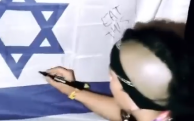 Un membre du groupe de hip-hop espagnol Tribade vandalisant un drapeau israélien lors du festival de musique Sziget, en Hongrie, le 14 août 2022. (Crédit : Instagram)