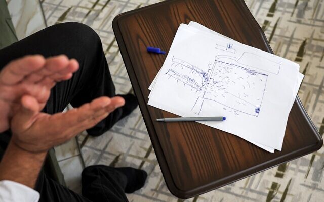 Mutassem Abd al-Sater, 42 ans, ancien détenu de la prison de Sednaya, dessine un croquis rudimentaire du plan de la prison lors d'un entretien à son domicile à Reyhanli, dans la province de Hatay, dans le sud de la Turquie, près de la frontière avec la Syrie, le 10 août 2022. (Crédit : OMAR HAJ KADOUR / AFP)