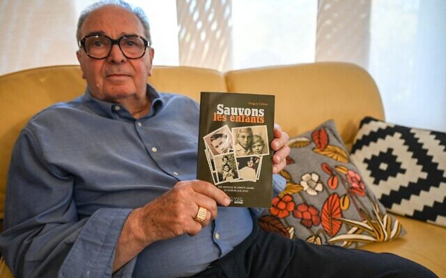 Eric Adamski, 84 ans, survivant du sauvetage d'enfants à la gare de Lille le 11 septembre 1942, alors qu'il avait 4 ans, chez lui, à Lille, dans le nord de la France, tenant un livre relatant l'histoire de ce sauvetage, le 6 septembre 2022. (Crédit : DENIS CHARLET / AFP) Eric Adamski, 84 ans, survivant du sauvetage d'enfants à la gare de Lille le 11 septembre 1942, alors qu'il avait 4 ans, chez lui, à Lille, dans le nord de la France, tenant un livre relatant l'histoire de ce sauvetage, le 6 septembre 2022. (Crédit : DENIS CHARLET / AFP)