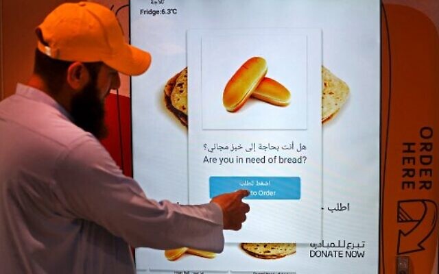 Un homme commandant des articles dans un distributeur automatique qui distribue du pain gratuit, à Dubaï, le 22 septembre 2022. (Crédit : Karim Sahib/AFP) Un homme commandant des articles dans un distributeur automatique qui distribue du pain gratuit, à Dubaï, le 22 septembre 2022. (Crédit : Karim Sahib/AFP)