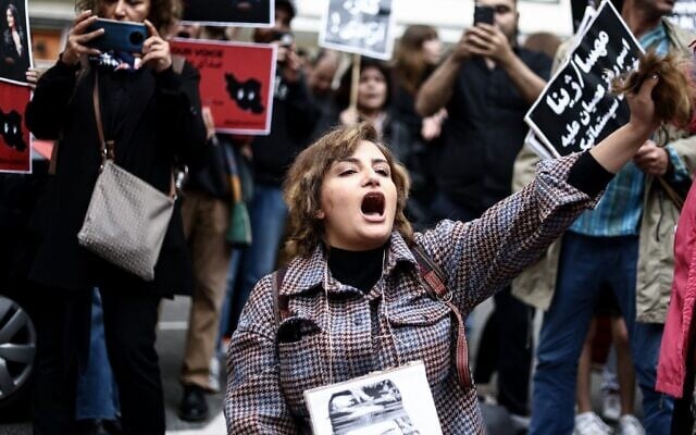 Illustration : Une femme se coupant les cheveux lors d'une manifestation de soutien à Mahsa Amini devant l'ambassade d'Iran, à Bruxelles, le 23 septembre 2022. (Crédit : Kenzo Tribouillard/AFP) Illustration : Une femme se coupant les cheveux lors d'une manifestation de soutien à Mahsa Amini devant l'ambassade d'Iran, à Bruxelles, le 23 septembre 2022. (Crédit : Kenzo Tribouillard/AFP)