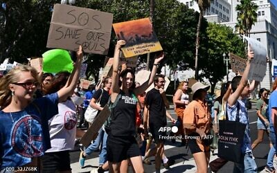 Des jeunes et des militants de Los Angeles tenant des pancartes alors qu'ils participent à une grève mondiale pour le climat visant à déclarer une urgence de justice climatique devant l'hôtel de ville de Los Angeles, le 23 septembre 2022.
(Crédit : Frederic J. Brown/AFP)