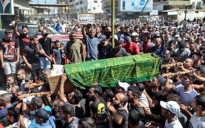Des personnes en deuil marchant avec le corps d'une des victimes qui s'est noyée dans le naufrage d'un bateau de migrants qui a coulé au large des côtes syriennes, lors de ses funérailles après le retour de son corps dans le camp de réfugiés de Nahr al-Bared, dans la banlieue de la ville de Tripoli, dans le nord du Liban, le 24 septembre 2022. (Crédit : Fathi al-Masri/AFP)