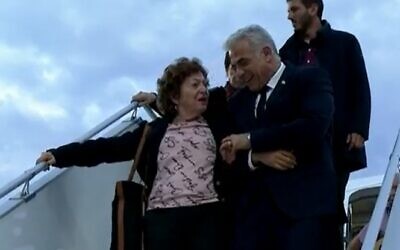 Le Premier ministre Yair Lapid (R) aide une survivante de la Shoah, Shoshana Trister, à descendre de l'avion après avoir été submergée par l'émotion en voyant des soldats allemands à son arrivée à Berlin, le 12 septembre 2022 (Crédit : Capture d’écran/Douzième chaîne)