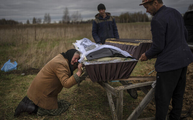 Nadiya Trubchaninova, 70 ans, pleure en tenant le cercueil de son fils Vadym, 48 ans, tué par des soldats russes le 30 mars dernier à Bucha, lors de ses funérailles au cimetière de Mykulychi, dans la banlieue de Kiev, en Ukraine, le 16 avril 2022. (Crédit : Rodrigo Abd/AP)