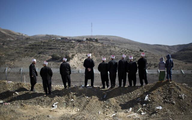 Des Druzes regardent au-delà de la frontière entre Israël et la Syrie, près de  Majdal Shams, sur le plateau du Golan, le 14 février 2014. (Crédit : AP/Oded Balilty)