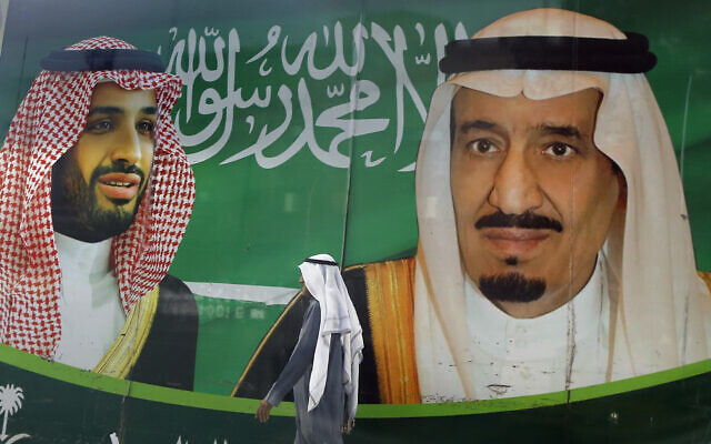 Un homme marche devant une bannière montrant le roi saoudien Salman, à droite, et le prince héritier Mohammed bin Salman aux abords d'un centre commerciale à Jeddah, en Arabie saoudite, le 7 mars 2020. (Crédit : AP Photo/Amr Nabil, File) Un homme marche devant une bannière montrant le roi saoudien Salman, à droite, et le prince héritier Mohammed bin Salman aux abords d'un centre commerciale à Jeddah, en Arabie saoudite, le 7 mars 2020. (Crédit : AP Photo/Amr Nabil, File)