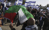 Un Palestinien brandissant son drapeau national alors que des Israéliens lèvent le leur à l'occasion de Yom Yeroushalayim, dans la Vieille Ville de Jérusalem, le 29 mai 2022.  (Crédit : AP Photo/Mahmoud Illean)