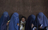 Des femmes afghanes attendent de recevoir de l'argent à un point de distribution d'argent organisé par le Programme alimentaire mondial, à Kaboul, en Afghanistan, le 20 novembre 2021 (Crédit : AP/Petros Giannakouris, File)