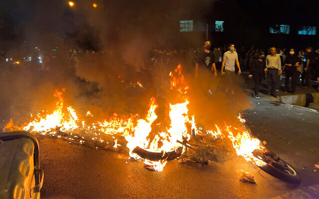 Une moto de la police incendiée pendant une manifestation suite à la mort d'une jeune femme placée en détention pour avoir contrevenu au code vestimentaire strict du pays, dans le centre de Téhéran, en Iran, le 19 septembre 2022. (Crédit : AP Photo) Une moto de la police incendiée pendant une manifestation suite à la mort d'une jeune femme placée en détention pour avoir contrevenu au code vestimentaire strict du pays, dans le centre de Téhéran, en Iran, le 19 septembre 2022. (Crédit : AP Photo)