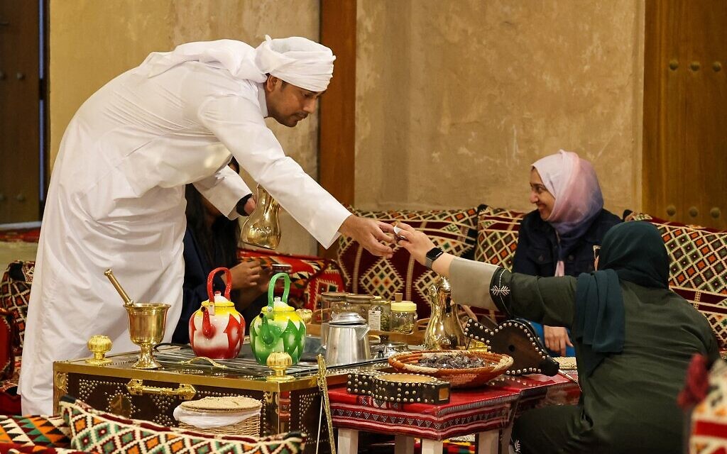 Des visiteurs se voient servir du "gahwa" traditionnel, préparé en torréfiant des grains de café puis en les faisant bouillir avec de la cardamome et du safran, à la maison culturelle Embrace Doha dans le souk al-Wakrah, au sud de la capitale Doha, le 13 septembre 2022. (Crédit : Karim JAAFAR / AFP) Des visiteurs se voient servir du "gahwa" traditionnel, préparé en torréfiant des grains de café puis en les faisant bouillir avec de la cardamome et du safran, à la maison culturelle Embrace Doha dans le souk al-Wakrah, au sud de la capitale Doha, le 13 septembre 2022. (Crédit : Karim JAAFAR / AFP)
