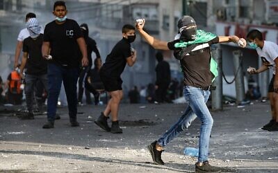 Illustration : De jeunes Palestiniens jetant des pierres aux forces de l’ordre israéliennes lors d’affrontements dans le camp de réfugiés de Shuafat, à Jérusalem-Est, le 12 octobre 2022 (Crédit: Ahmad Gharabli/AFP)
