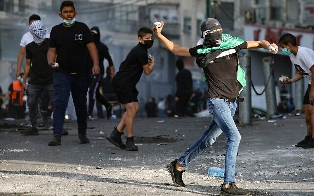 Illustration : De jeunes Palestiniens jetant des pierres aux forces de l’ordre israéliennes lors d’affrontements dans le camp de réfugiés de Shuafat, à Jérusalem-Est, le 12 octobre 2022 (Crédit: Ahmad Gharabli/AFP) Illustration : De jeunes Palestiniens jetant des pierres aux forces de l’ordre israéliennes lors d’affrontements dans le camp de réfugiés de Shuafat, à Jérusalem-Est, le 12 octobre 2022 (Crédit: Ahmad Gharabli/AFP)