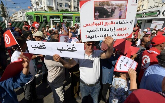 Des partisans du parti Destourien brandissant des drapeaux nationaux et levant des pancartes lors d'une manifestation contre le président Kais Saied, dans la capitale Tunis, le 15 octobre 2022. (Crédit : Fethi Belaid/AFP) Des partisans du parti Destourien brandissant des drapeaux nationaux et levant des pancartes lors d'une manifestation contre le président Kais Saied, dans la capitale Tunis, le 15 octobre 2022. (Crédit : Fethi Belaid/AFP)