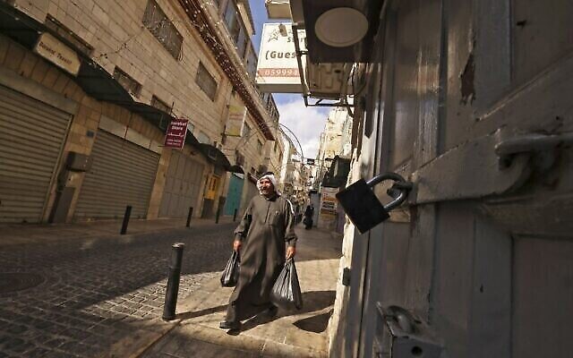 Un Palestinien passe devant des magasins, fermés par solidarité un jour après qu'Udai Tamimi - un terroriste palestinien recherché par Israël pour avoir tué une soldate et blessé grièvement un garde - a été tué après une chasse à l'homme de 10 jours alors qu'il tirait sur des gardes de sécurité israéliens, près de la place de la Nativité dans la ville biblique de Bethléem en Cisjordanie le 20 octobre 2022. (Crédit : HAZEM BADER / AFP) Un Palestinien passe devant des magasins, fermés par solidarité un jour après qu'Udai Tamimi - un terroriste palestinien recherché par Israël pour avoir tué une soldate et blessé grièvement un garde - a été tué après une chasse à l'homme de 10 jours alors qu'il tirait sur des gardes de sécurité israéliens, près de la place de la Nativité dans la ville biblique de Bethléem en Cisjordanie le 20 octobre 2022. (Crédit : HAZEM BADER / AFP)