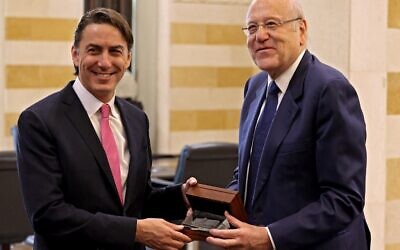 Illustration : Le Premier ministre libanais Najib Mikati, à droite, présentant à Amos Hochstein, l'envoyé américain chargé de la médiation de la frontière maritime libano-israélienne, un cadeau représentant un hologramme du palais du gouvernement libanais lors de leur rencontre au palais de la capitale libanaise Beyrouth, le 27 octobre 2022. (Crédit : Joseph Eid/AFP)