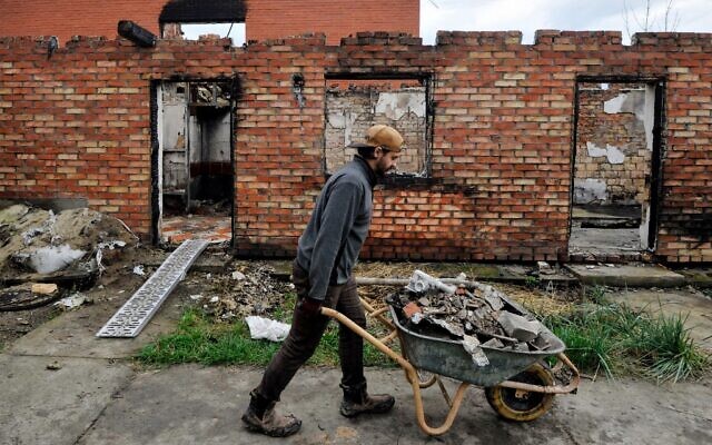Un volontaire débarrasse les décombres d'une maison détruite à la suite d'un bombardement dans le village de Moshchun, dans la région de Kiev, le 29 octobre 2022, en pleine invasion russe de l'Ukraine. (Crédit : Sergei CHUZAVKOV / AFP) Un volontaire débarrasse les décombres d'une maison détruite à la suite d'un bombardement dans le village de Moshchun, dans la région de Kiev, le 29 octobre 2022, en pleine invasion russe de l'Ukraine. (Crédit : Sergei CHUZAVKOV / AFP)