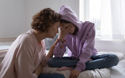 Un parent réconforte sa fille adolescente. Illustration (Crédit : fizkes ; iStock)
