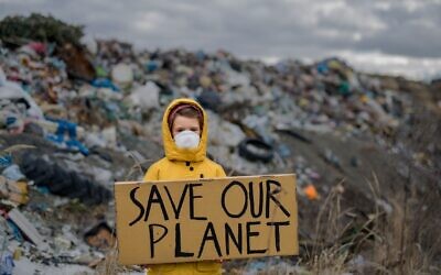 Un enfant se tient sur un site d'enfouissement de déchets avec un appel à sauver notre planète, le 12 juin 2020. (Crédit : Halfpoint/iStock/Getty Images) Un enfant se tient sur un site d'enfouissement de déchets avec un appel à sauver notre planète, le 12 juin 2020. (Crédit : Halfpoint/iStock/Getty Images)