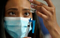 Sur cette photo du 19 mai 2021, on voit  une infirmière se préparer à administrer un vaccin contre la COVID-19 de Moderna, dans un centre de vaccination installé au stade Gillette de Foxborough, dans le Massachusetts. (Crédit : AP Photo/Steven Senne)
