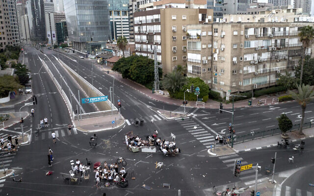  De jeunes Israéliens assis à un carrefour sur une route sans voiture pendant Yom Kippour à Ramat Gan, le 5 octobre 2022. (Crédit : AP Photo/Oded Balilty)