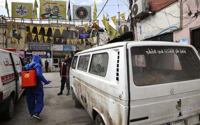 Un travailleur palestinien de l'UNRWA (Agence de secours et de travaux des Nations unies) pulvérise une camionnette, transportant du pain, par précaution contre le coronavirus, à l'entrée fermée de Jalil, ou camp de réfugiés palestiniens de Galilée, à Baalbek, au Liban, le 24 avril 2020. (Crédit : AP Photo/Hussein Malla) Un travailleur palestinien de l'UNRWA (Agence de secours et de travaux des Nations unies) pulvérise une camionnette, transportant du pain, par précaution contre le coronavirus, à l'entrée fermée de Jalil, ou camp de réfugiés palestiniens de Galilée, à Baalbek, au Liban, le 24 avril 2020. (Crédit : AP Photo/Hussein Malla)