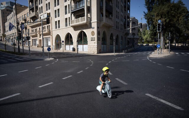  Des personnes roulant à vélo et marchant le long de la route vide, le jour de Yom Kippour, la plus sainte des fêtes juives, à Jérusalem, le 4 octobre 2022. (Crédit : Yonatan Sindel/Flash90)
 