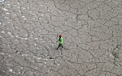 Un homme marche le long d'un lit de rivière asséché sur les rives du Gange, à Prayagraj, le 14 novembre 2022. (Crédit : SANJAY KANOJIA / AFP)