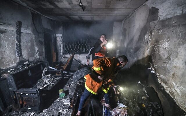 Des pompiers palestiniens éteignent les flammes dans un appartement ravagé par un incendie dans le camp de Jabaliya, dans le nord de la bande de Gaza, le 17 novembre 2022. (Crédit : MAHMUD HAMS / AFP)