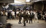 Les forces de sécurité israéliennes déployant des moyens de dispersion des émeutes au milieu d'altercations entre Israéliens et Palestiniens, sur le chemin de la visite de la tombe d'Othniel dans la ville de Hébron, en Cisjordanie, le 19 novembre 2022. (Crédit : Hazem Bader/AFP)