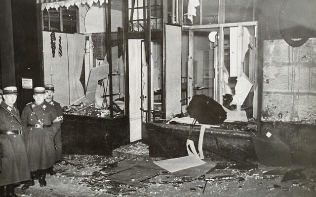 Des nazis se tiennent près de propriétés juives saccagées pendant la Nuit de Cristal, probablement dans la ville de Fürth, en Allemagne, le 10 novembre 1938. (Crédit : Yad Vashem via AP)