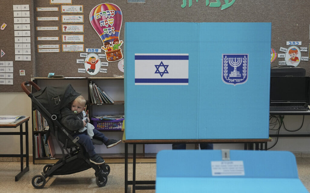 Un jeune enfant attend que son père vote dans à Kiryat Arba, en Cisjordanie, lors des élections en Israël, le 1er novembre 2022. (Crédit : AP Photo/Tsafrir Abayov)