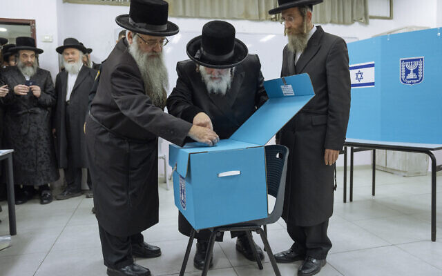 Des juifs ultra-orthodoxes regardent le rabbin Israel Hager voter lors des élections israéliennes à Bnei Brak, le 1er novembre 2022. (Crédit : AP Photo/Oded Balilty)