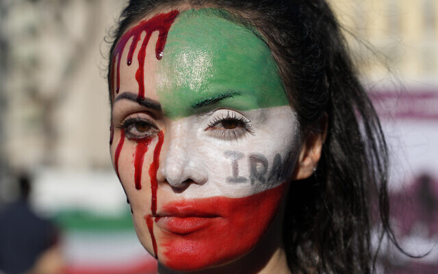 Lors d'un rassemblement dans le centre de Rome, le samedi 29 octobre 2022, une femme dont le visage est scindé en deux : d'un côté du rouge sang qui dégouline et de l'autre le drapeau de l'Iran, en mémoire à la mort de Mahsa Amini, une femme décédée alors qu'elle était en garde à vue en Iran.(Crédit : AP Photo/Gregorio Borgia ) Lors d'un rassemblement dans le centre de Rome, le samedi 29 octobre 2022, une femme dont le visage est scindé en deux : d'un côté du rouge sang qui dégouline et de l'autre le drapeau de l'Iran, en mémoire à la mort de Mahsa Amini, une femme décédée alors qu'elle était en garde à vue en Iran.(Crédit : AP Photo/Gregorio Borgia )