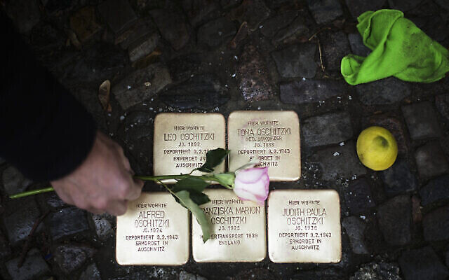 Juergen Schulz, un habitant du quartier, déposant une fleur après avoir poli les "Stolpersteine" ou "pierres d'achoppement" commémorant les personnes déportées et tuées par les nazis, devant sa maison à Berlin, en Allemagne, le 9 novembre 2021. (Crédit : Markus Schreiber/AP) Juergen Schulz, un habitant du quartier, déposant une fleur après avoir poli les "Stolpersteine" ou "pierres d'achoppement" commémorant les personnes déportées et tuées par les nazis, devant sa maison à Berlin, en Allemagne, le 9 novembre 2021. (Crédit : Markus Schreiber/AP)