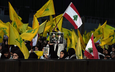 Un partisan du Hezbollah tenant une photo du guide suprême iranien, l'ayatollah Ali Khamenei, à droite, et du général Qassem Soleimani, de la force Quds, tué par un drone américain à Bagdad, à gauche, lors d'un rassemblement marquant la Journée des martyrs du Hezbollah, au Liban, le 11 novembre 2022. (Crédit : AP Photo/Bilal Hussein)