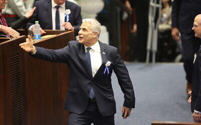 Le Premier ministre sortant, Yair Lapid, serre des mains lors de la cérémonie de prestation de serment de la nouvelle Knesset, au Parlement de Jérusalem, le 15 novembre 2022. (Crédit : Abir Sultan/Pool Photo via AP)
