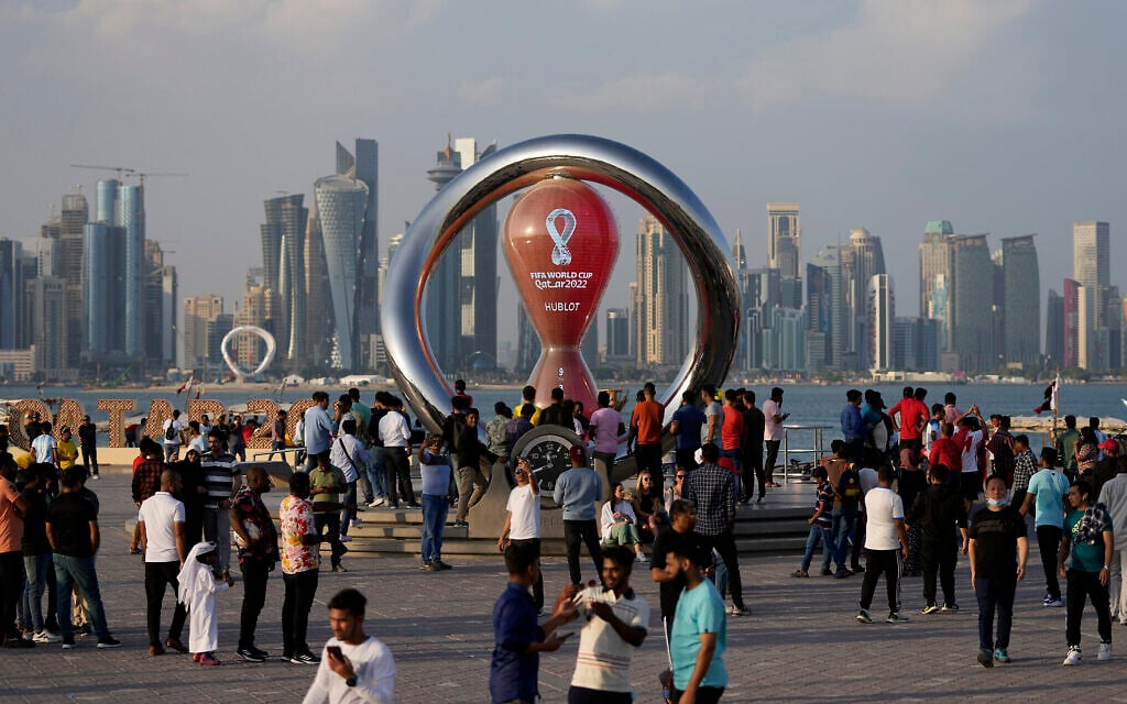 Des personnes rassemblées autour de l'horloge officielle du compte à rebours indiquant le temps restant avant le coup d'envoi de la Coupe du monde à Doha, au Qatar, le 11 novembre 2022. (Crédit : AP Photo/Hassan Ammar)