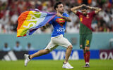 Un homme court sur le terrain de foot avec un drapeau arc-en-ciel lors du match de la Coupe du monde entre le Portugal et l'Uruguay, au stade Lusail, au Qatar, le lundi 28 novembre 2022. (Crédit : AP/Abbie Parr)