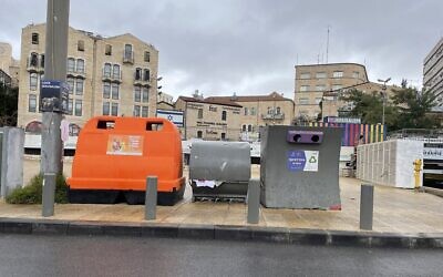 Une poubelle orange pour le recyclage des déchets et des emballages près d'un conteneur à papier et d'une poubelle à verre, place  Hatulot, dans le centre de Jérusalem, le 27 novembre 2022. (Crédit : Sue Surkes/Times of Israel)